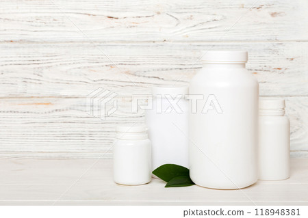 supplement pills with medicine bottle health care and medical top view. Vitamin tablets. Top view mockup bottle for pills and vitamins with green leaves, natural organic bio supplement, copy space 118948381