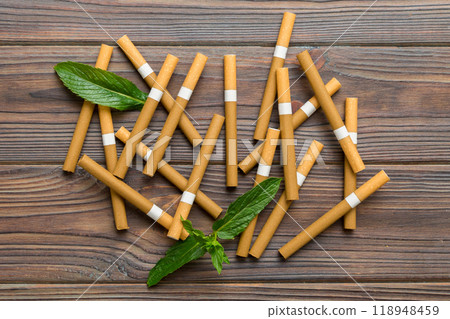 Menthol cigarettes and fresh mint leaves on colored background, Many cigarettes stacked together top view flat lay Menthol cigarettes and fresh mint leaves on colored background, Many cigarettes stacked together top view flat lay 118948459