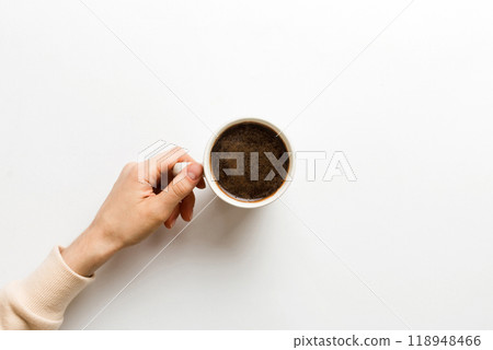 Minimalistic style woman hand holding a cup of coffee on Colored background. Flat lay, top view cappuccino cup. Empty place for text, copy space. Coffee addiction. Top view, flat lay 118948466