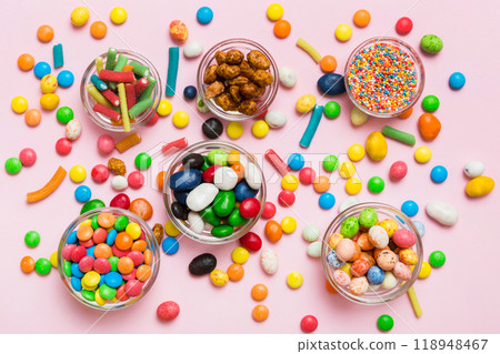 different colored round candy in bowl and jars. Top view of large variety sweets and candies with copy space different colored round candy in bowl and jars. Top view of large variety sweets and candies with copy space 118948467