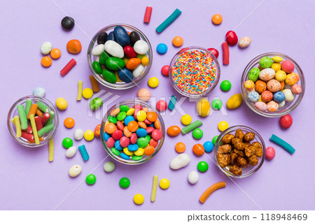 different colored round candy in bowl and jars. Top view of large variety sweets and candies with copy space different colored round candy in bowl and jars. Top view of large variety sweets and candies with copy space 118948469