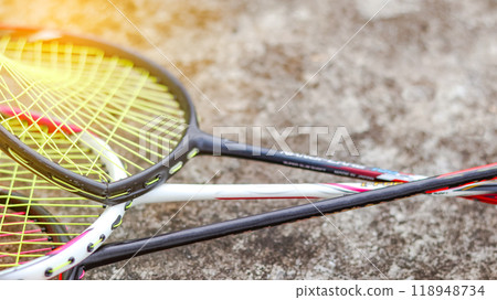 Broken badminton rackets lying on a dark surface, conveying the idea that sports and exercise are better alternatives to violence in society, promoting peace and healthy living. 118948734