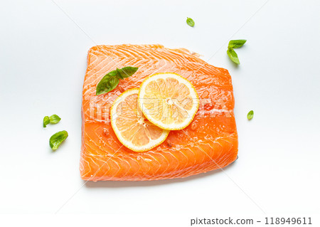 Fresh raw salmon marbled fillet isolated on white background with lemon, coarse salt, green herbs top view. Healthy nutrition and balanced diet 118949611