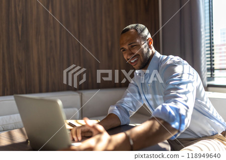 Young man sitting at his desk in the office and working on laptop Young man sitting at his desk in the office and working on laptop 118949640