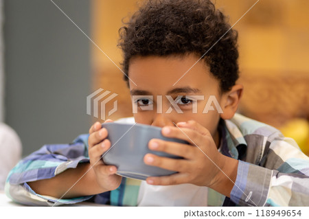 Curly-haired boy sitting in the kitchen and drinking milk Curly-haired boy sitting in the kitchen and drinking milk 118949654