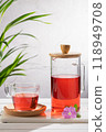 Red fruit infusion in crystal glass and pitcher on wooden base. Vertical format. 118949708