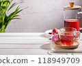 Red fruit infusion in crystal glass and pitcher on wooden base with copy space. 118949709