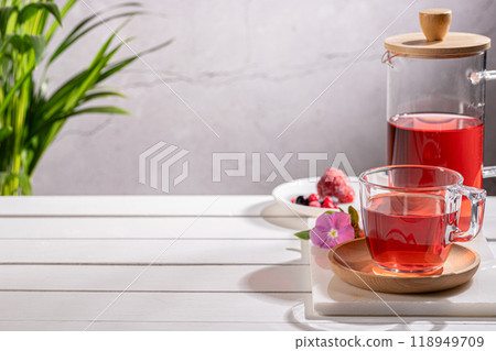 Red fruit infusion in crystal glass and pitcher on wooden base with copy space. Red fruit infusion in crystal glass and pitcher on wooden base with copy space. 118949709