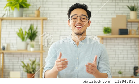 Happy Asian Man with Glasses Gesturing and Smiling in Casual Setting 118949853