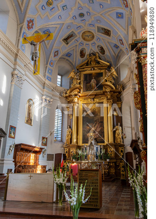 Explore the stunning interior of a Baroque church featuring an ornate golden altar, vaulted ceiling with blue and gold designs, and religious artworks. Perfect for those interested in religious art an Explore the stunning interior of a Baroque church featuring an ornate golden altar, vaulted ceiling with blue and gold designs, and religious artworks. Perfect for those interested in religious art an 118949880