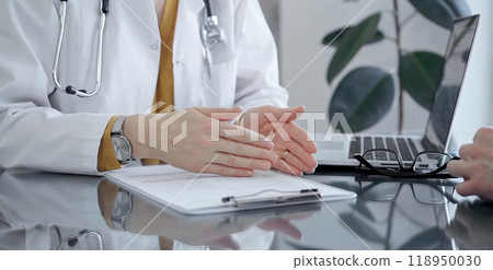 Doctor and patient consultation with clipboard and medication notes. Close-up view of unknown female doctor using a tablet during a patient consultation Doctor and patient consultation with clipboard and medication notes. Close-up view of unknown female doctor using a tablet during a patient consultation 118950030