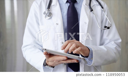 Doctor man wearing lab coat and stethoscope using tablet computer in hospital. Medicine and science 118950053