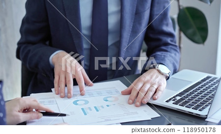 Professional businessman gestures to charts on laptop screen during corporate meeting. Business concept Professional businessman gestures to charts on laptop screen during corporate meeting. Business concept 118950178