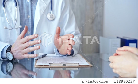 Doctor man and woman patient are discussing something and gesturing with their hands in medical office, close up. Medicine concept Doctor man and woman patient are discussing something and gesturing with their hands in medical office, close up. Medicine concept 118950237