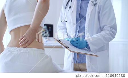 Doctor man wearing blue medical gloves is making notes on a clip 118950288