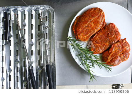 Raw meat before grilling. Top view of raw steak lying on a white plate 118950306