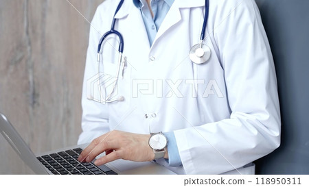 Doctor at work. Unrecognizable medical professional using laptop computer for healthcare research showcasing modern medical technology, close up 118950311