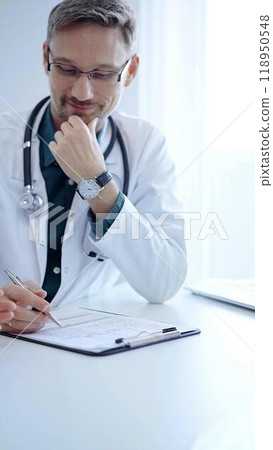 Doctor and a patient. The physician, wearing a white medical coat over a green shirt, gesturing with his hands during a consultation in the clinic. Medicine concept 118950548