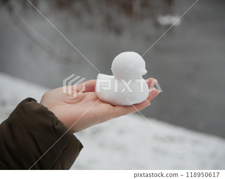 Snowman in the shape of ducks. Duck made of snow in a woman's hand 118950617