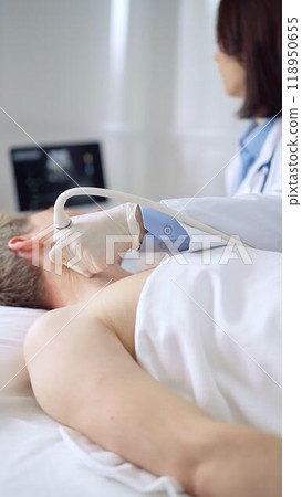 Doctor performing neck ultrasound exam on male patient 118950655