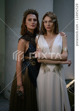 Two beautiful girls, sisters Lilith and Eva, pose in rocking dresses against the background of columns. Two beautiful girls, sisters Lilith and Eva, pose in rocking dresses against the background of columns. 118952529