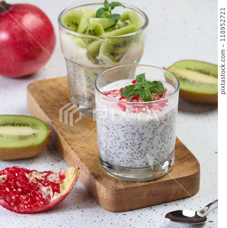 Two glasses of chia yogurt dessert garnished with fresh fruit, pomegranate seeds and kiwi slices 118952721