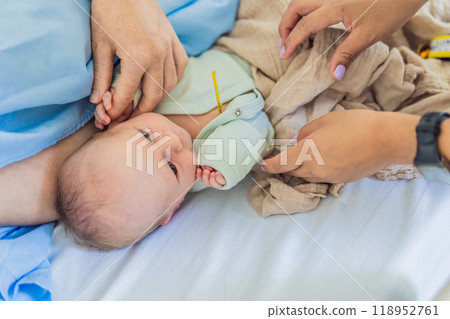 A nurse is taking a baby's temperature in the hospital. The gentle and careful procedure ensures the baby's comfort and well-being, allowing for accurate monitoring of their health 118952761