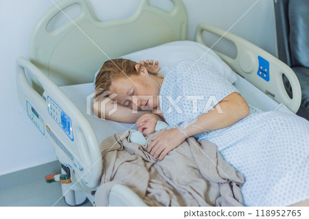 A baby lies with the mother after childbirth, resting peacefully. The serene moment captures the bond between mother and child as they begin their journey together. The hospital environment ensures a A baby lies with the mother after childbirth, resting peacefully. The serene moment captures the bond between mother and child as they begin their journey together. The hospital environment ensures a 118952765