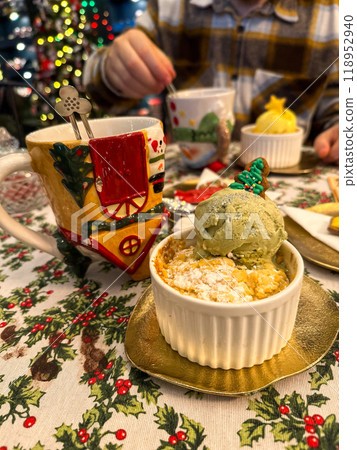 Festive dessert table with holiday-themed decorations. a warm crumble topped with a scoop of ice cream and a Christmas tree decoration captures the cozy atmosphere of a winter celebration. Festive and 118952940