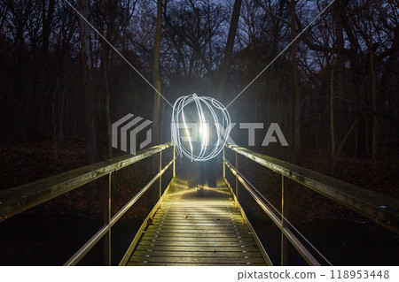 Light Painted Orb on Illuminated Forest Footbridge at Night 118953448