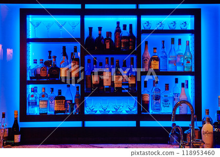Blue-Lit Upscale Bar Shelves with Spirits and Glassware Blue-Lit Upscale Bar Shelves with Spirits and Glassware 118953460