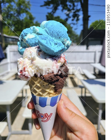 Triple Scoop Ice Cream Cone in Hand at Eye Level 118953490