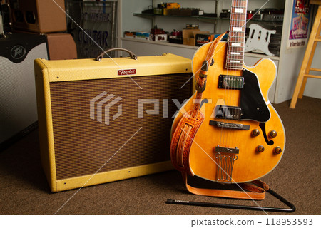 Vintage Yellow Electric Guitar Leaning on Amplifier in Music Shop 118953593
