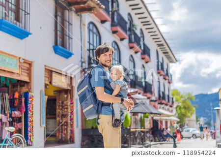 Father and his son tourists walks through the colonial streets San Cristobal de las Casas, Mexico. Cultural exploration, architecture, and travel experience concept Father and his son tourists walks through the colonial streets San Cristobal de las Casas, Mexico. Cultural exploration, architecture, and travel experience concept 118954224