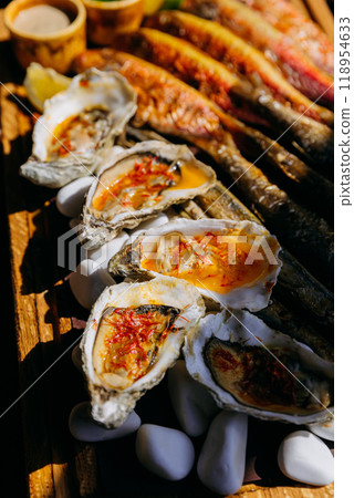 Grilled oysters with spicy sauce, seafood delicacy perfect for fine dining, restaurant menus Grilled oysters with spicy sauce, seafood delicacy perfect for fine dining, restaurant menus 118954633