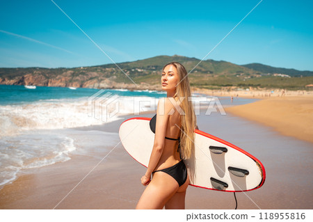 Sensuous surfer girl in bikini carrying surfboard 118955816