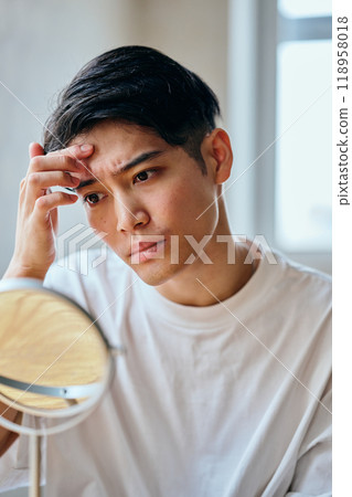 A young man in his 20s who is concerned about his skin 118958018