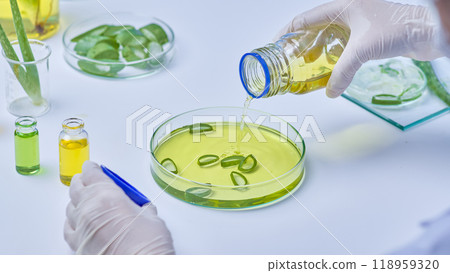 An example of a modern laboratory: instruments, liquids, and samples of aloe vera are all on the table. A scientist is adding fluids to samples of aloe vera in a petri dish. An example of a modern laboratory: instruments, liquids, and samples of aloe vera are all on the table. A scientist is adding fluids to samples of aloe vera in a petri dish. 118959320