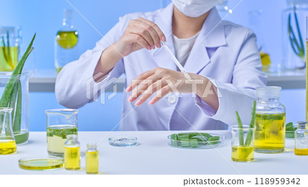 In a contemporary lab setup with glass jars and aloe ingredients ideal for the aloe experiment picture template, a scientist uses a glass rod to carefully apply a layer of transparent gel on hand. In a contemporary lab setup with glass jars and aloe ingredients ideal for the aloe experiment picture template, a scientist uses a glass rod to carefully apply a layer of transparent gel on hand. 118959342