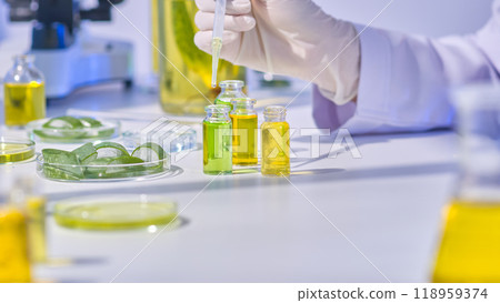 In the illustration sample, an aloe experiment in a lab environment is depicted, with a scientist dropping a solution into a green extraction vial amid other colored vials and aloe-filled petri plates In the illustration sample, an aloe experiment in a lab environment is depicted, with a scientist dropping a solution into a green extraction vial amid other colored vials and aloe-filled petri plates 118959374