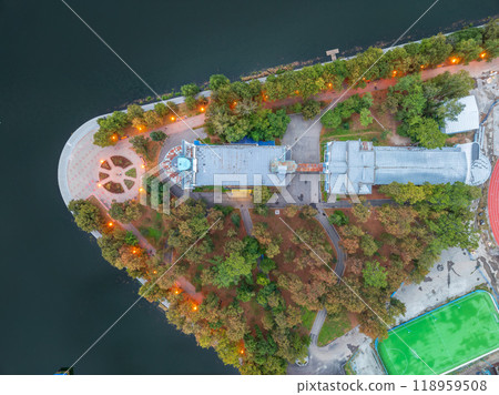 A top down, aerial view of the evening city park on the river bank. A top down, aerial view of the evening city park on the river bank. 118959508