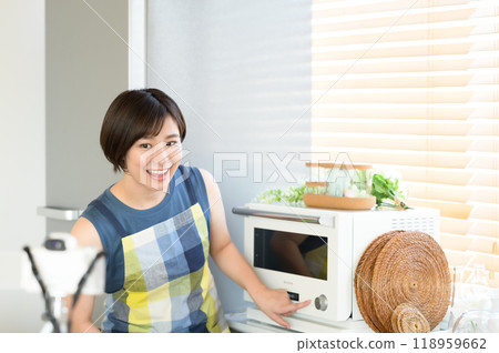 A woman recording a cooking video in front of a microwave A woman recording a cooking video in front of a microwave 118959662