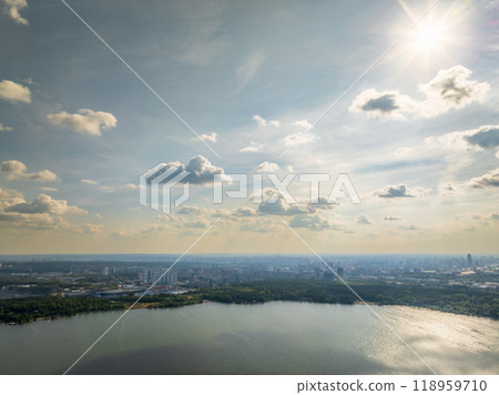 Big lake with green shores in bright sun light and city on horizon, aerial landscape. Recreation concept. Aerial view Big lake with green shores in bright sun light and city on horizon, aerial landscape. Recreation concept. Aerial view 118959710