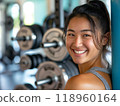 在訓練館裡拿著啞鈴的微笑的年輕女子 118960164