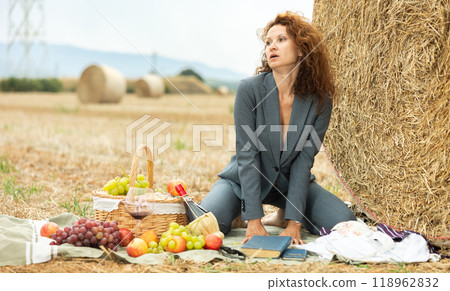 Sensual woman in business suit relaxing during picnic alone near haystack Sensual woman in business suit relaxing during picnic alone near haystack 118962832