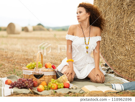 Pretty woman in white dress near haystack on picnic 118962896