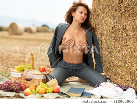 Portrait of sexy woman with glass of wine on farm field near hay bales 118962906