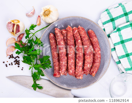 Traditional spanish dish. Longaniza, pork sausage on plate with herbs and cutlery Traditional spanish dish. Longaniza, pork sausage on plate with herbs and cutlery 118962914