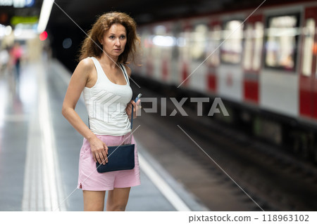 Adult woman stands at subway station Adult woman stands at subway station 118963102