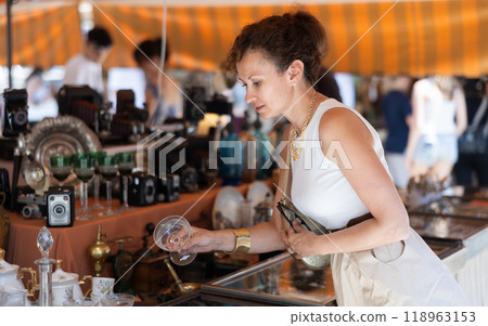 Woman in flea market store look at Chinese porcelain glass , antique gifts Woman in flea market store look at Chinese porcelain glass , antique gifts 118963153